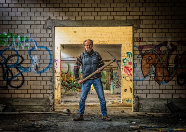 scary Man with axe standing in abandoned building with graffitti
