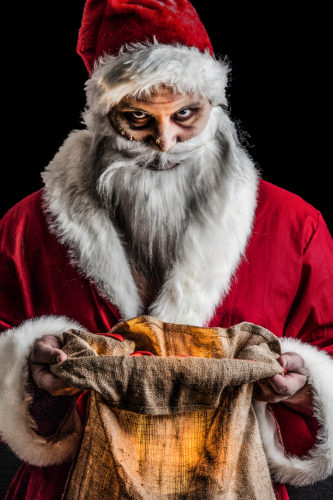 Creepy scary Santa holding open a dirty bag in a menacing way