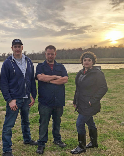 Ghosts of Morgan City Cast Ben Hansen, Jereme Leonard, and Sarah Lemos standing by the shore at sunset.