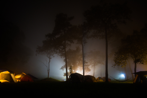 Eerie silhouettes of tents in a fog shrouded night