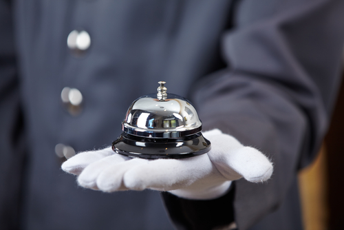 Concierge hand wearing white glove holding bell