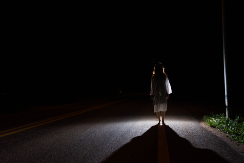 Ghostly figure on a dark empty road