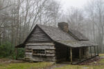 Creepy abandoned log settler's cabin in misty woods