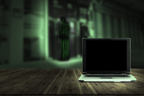 Ghostly computer laptop with shadow figures and a green heu