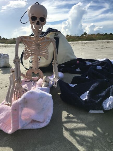 Skeleton at the beach with towel and beach bag