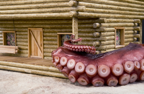 Giant octopus tentacle wrapped around a lob cabin porch post