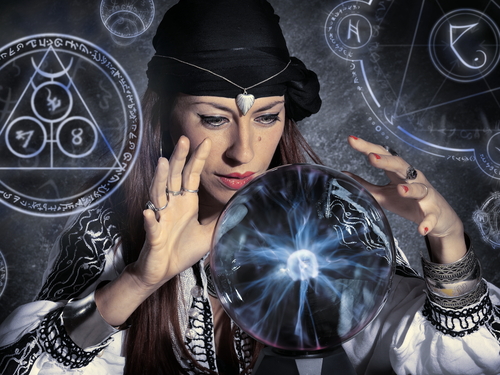 A gypsy psychic witch woman gazing into a crystal ball against an occult background