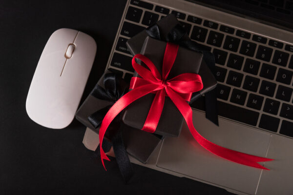 Laptop with gifts in black paper and red ribbon symbolizing virtual gift experiences