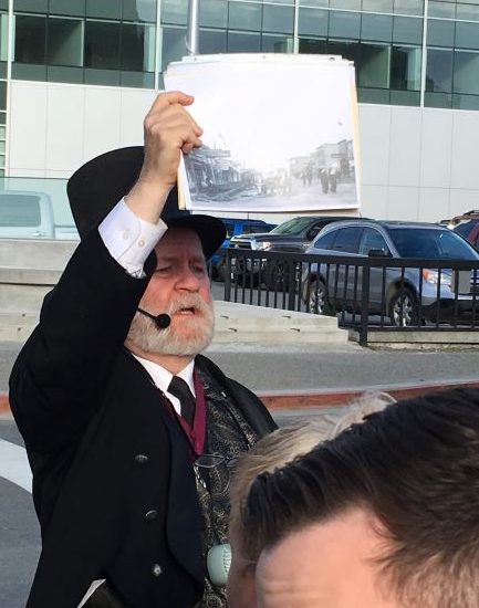 Anchorage ghost tour guide Rick Goodfellow holds up a historic photo during a tour.