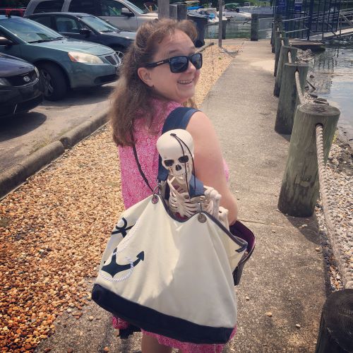 Courtney Mroch with Smalls skeleton in a tote bag at a marina
