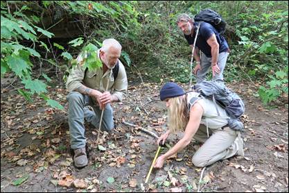 Mireya Mayor, Russell Acord and Ronny LeBlanc measure what appears to be a Bigfoot footprint in the mud.