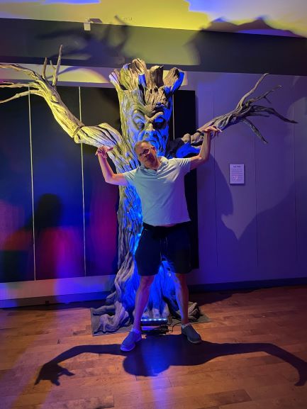 Man posing with tree at Distortions Monster World