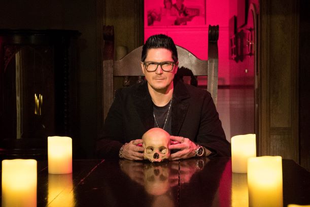 Zak Bagans at table with skull and candles for Haunted Museum series