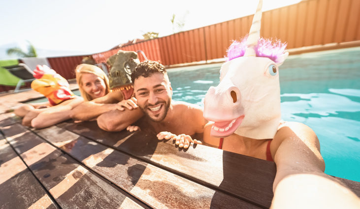 Crazy friends selfie doing pool party wearing bizarre mask - Young people having fun celebrating summer in exclusive tropical resort - Friendship and youth holidays lifestyle concept