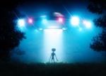 Silhouette of alien standing in beam of light from UFO hovering above the ground.