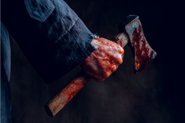 Man's hand holding bloody axe