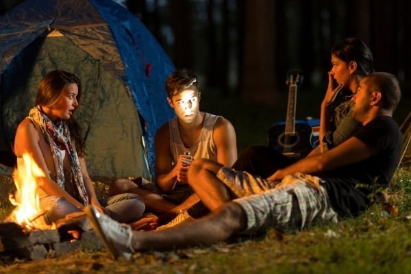 Campers sitting around a campfire at night telling scary stories