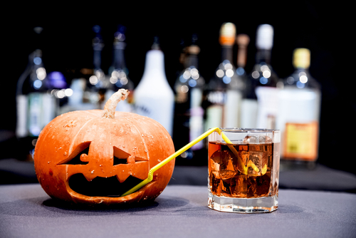 Funny Jack o lantern with straw drinking a cocktail through a straw 