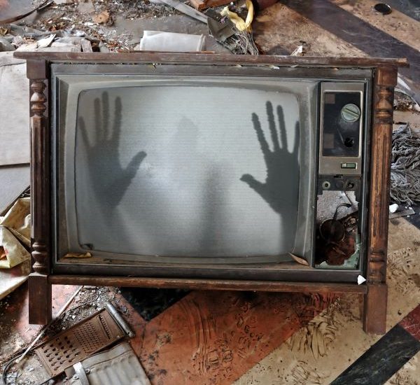 Ghostly hands pushing on screen from inside haunted TV