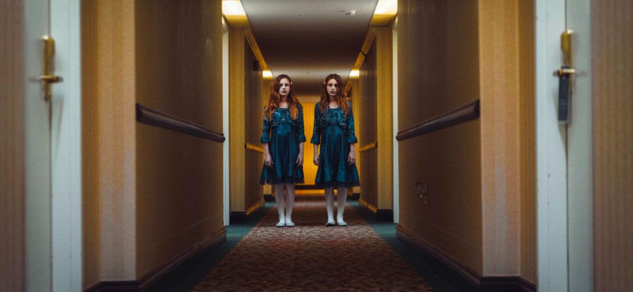 Two little girls like from The Shining standing in a hallway