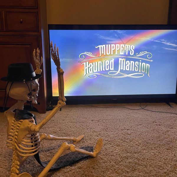 Skeleton cheering at end of Muppets Haunted Mansion with rainbow background