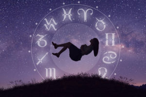 silhouette of woman floating in circle of astrology horoscope symbols