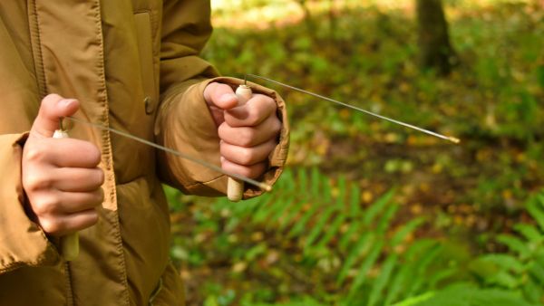 Man holding dowsing rods in forest