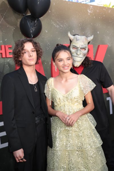 Mason Thames and Madeleine McGraw pose with the Grabber during the premiere of The Black Phone.