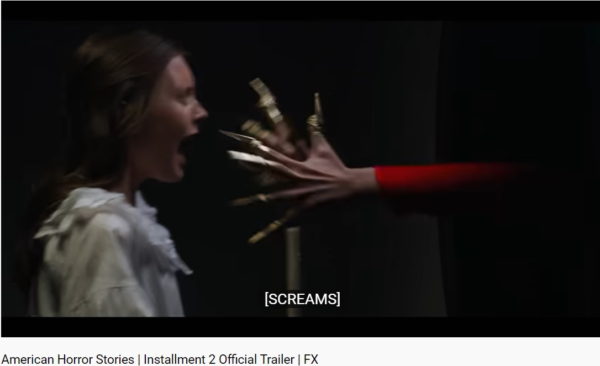 Screenshot of girl in white with candle and scary arm from American Horror Stories season 2