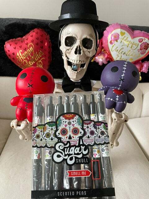 Smalls skeleton in top hat and bowtie with red and purp0le voodoo dolls and sugar skull pens for Valloween 2023