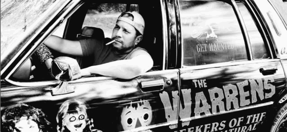 Dan Rivera in car smoking cigarette with Annabelle doll and Warren Occult Museum painted on the door